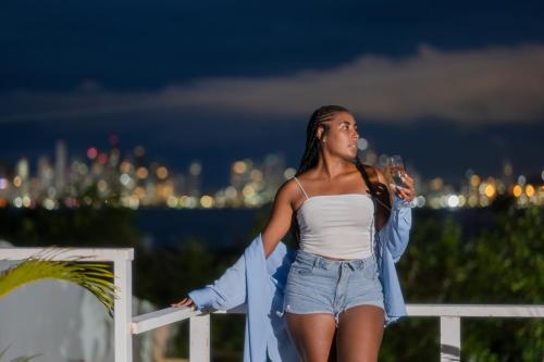 a woman standing on a fence with a glass of wine at Tiny Village Cartagena Boutique Resort in Tierra Bomba