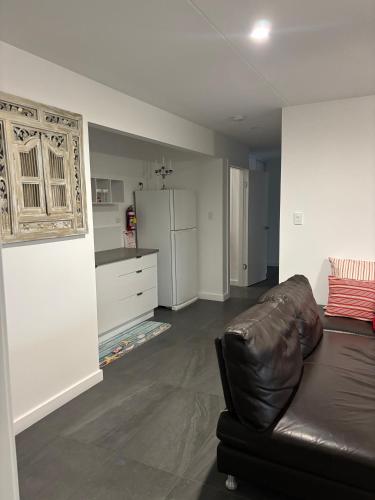 a living room with a leather couch and a kitchen at Quiet haven in Forster