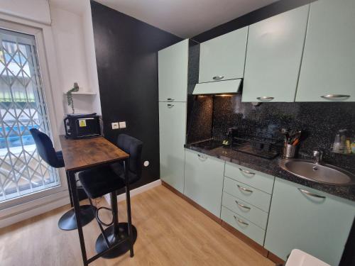 une cuisine avec des armoires blanches, une table et un évier dans l'établissement Aya's Studio, à Nice