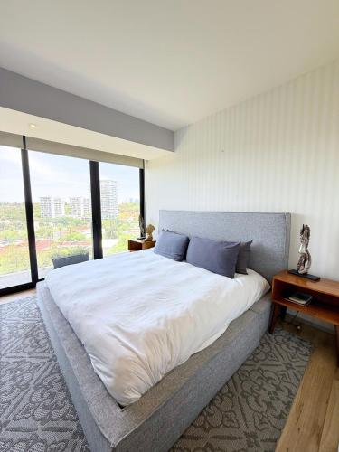 a bedroom with a large bed with a desk and windows at Departamento Grand 4H-154 in Guadalajara