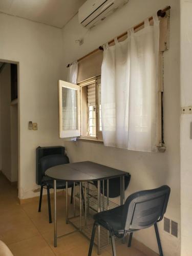 Una mesa y sillas en una habitación con ventana. en Casa de Invitados 2, en Pergamino