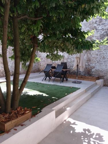 a patio with two chairs and a tree at Le Jardin Niortais - Hyper centre- proche gare - Paisible - Grand Jardin privé, WIFI HD -NETFLIX in Niort