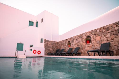 una piscina con sedie accanto a un edificio di Celeste Apartments a Ornos