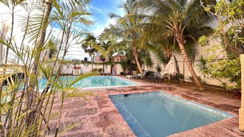 een zwembad met palmbomen voor een huis bij Íkaro Suites Cancún in Cancun