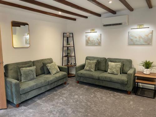 a living room with two green couches and a mirror at Central Kirkwall House in Orkney