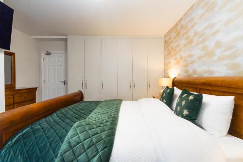 a bedroom with a bed with a green comforter at Dublin Premier Homestay in Ráth Cúil