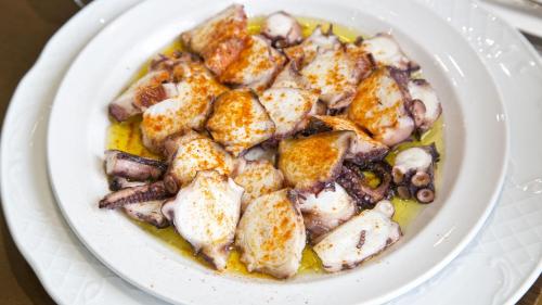 a white plate of food with chicken and mushrooms at Hotel Carlos 96 in Melide
