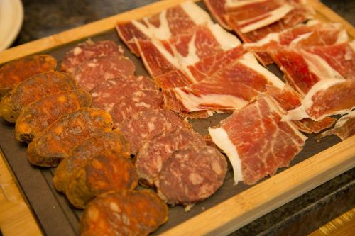 a tray of different types of meat on a table at Hotel Carlos 96 in Melide