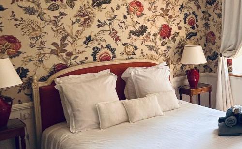 a bedroom with a bed with white sheets and floral wallpaper at Manoir de Daubeuf in Daubeuf-Serville
