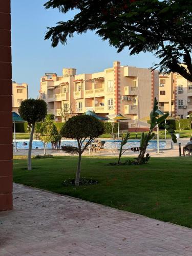 a park with trees and buildings in the background at Marselia Beach 1 Camellia in El Alamein