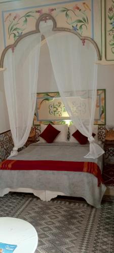 a bedroom with a canopy bed with red pillows at Dar Baaziz 3 in Sousse