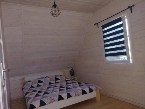 a bedroom with a bed in a room with a window at Biały domek nad jeziorem in Stegers