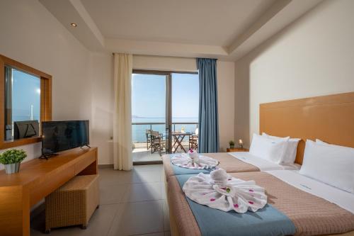 a hotel room with two beds and a television at Creteco Hotel & Suites in Gournes