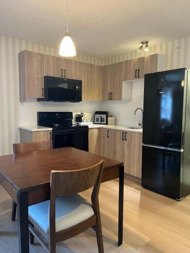 a kitchen with a wooden table and a black refrigerator at Prestige Prince George Lodge in Prince George