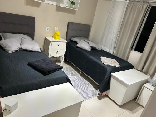 a bedroom with two beds and a desk and a window at ECONÔMICO, qtos na BEIRA DA PRAIA, confortável in Balneário Camboriú