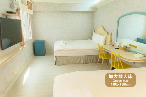 a room with a bed and a desk and a tv at Elizabeth Hotel in Taichung