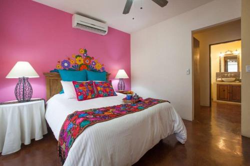 a bedroom with a large bed with a pink wall at 20 ft to malecón, downtown, private Pool in La Paz