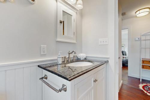 ein weißes Badezimmer mit Waschbecken und Spiegel in der Unterkunft Hen Cove Cottage in Pocasset