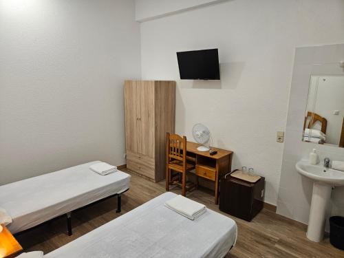 马德里米拉尔瓦旅馆的客房设有两张床、一张桌子和一个水槽