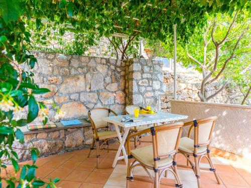 a table and chairs on a patio with a stone wall at Apartments Kirigin in Dubrovnik