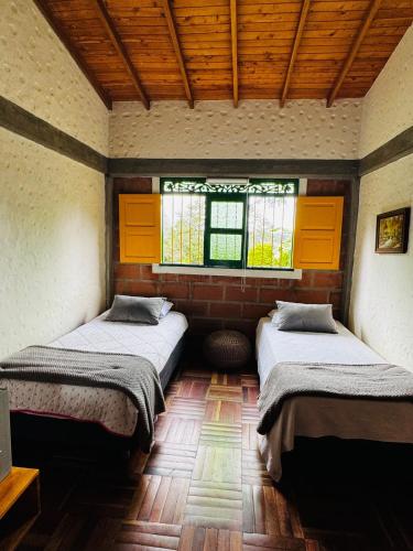 two beds in a room with two windows at Magical farmhouse near Arví Park in Mazo