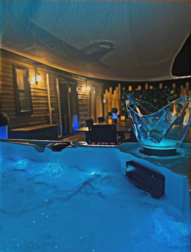 a tub filled with blue water with a glass at SPA et SAUNA de la presle in Saint-Georges-sur-Arnon