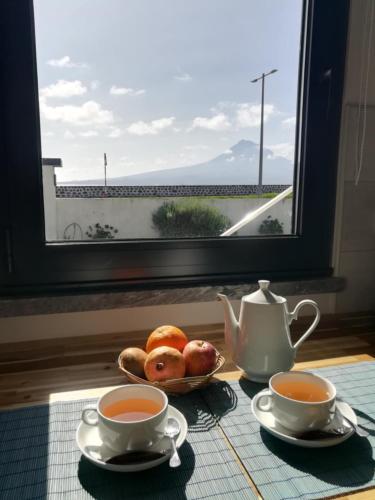 a table with two cups of tea and a plate of food at Seacrets Beach House in Praia do Almoxarife