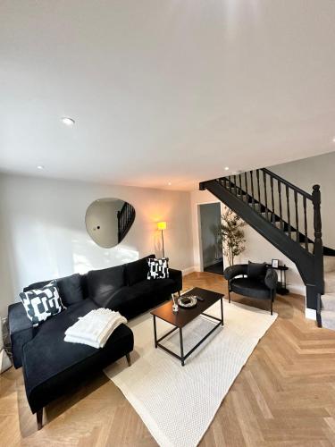a living room with a black couch and a staircase at Convenient City House By Ankers Contractors Accommodation Manchester With Free Parking in Manchester