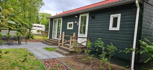 a black tiny house with a porch and a patio at De Kleine kriemelkuil-Het Koentje in Ermelo