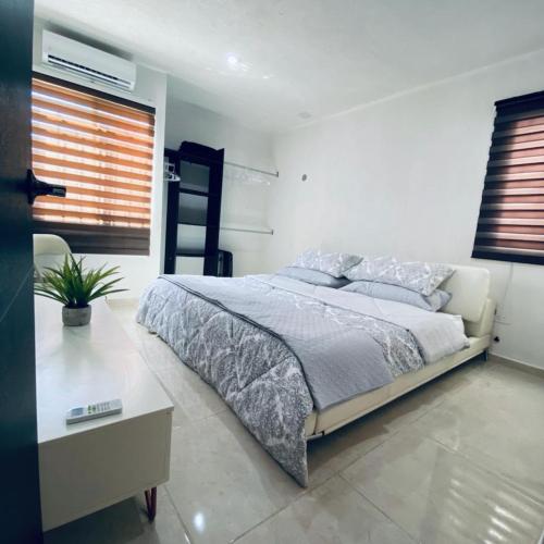a white bedroom with a bed and a table at Casa venue in Mérida