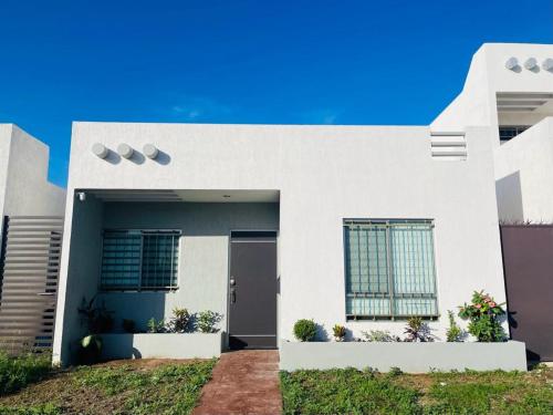a white house with a door and some plants at Casa venue in Mérida