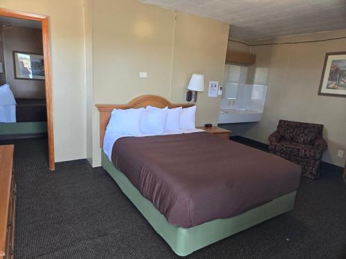 a hotel room with a bed and a chair at A Bridge View Inn in Chamberlain