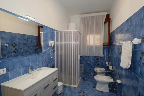 a blue tiled bathroom with a toilet and a sink at Villa Dolce Vita rooms in Castelluzzo