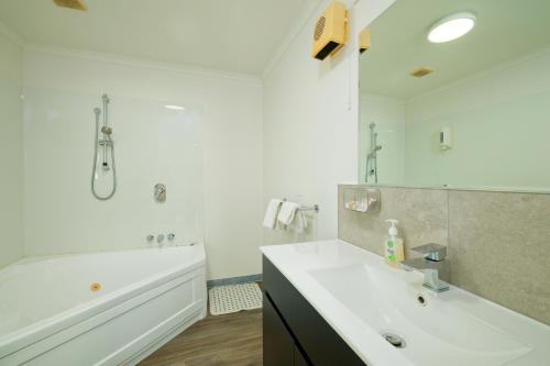 a white bathroom with a tub and a sink and a bath tub at Blue Seas Motel in Kaikoura