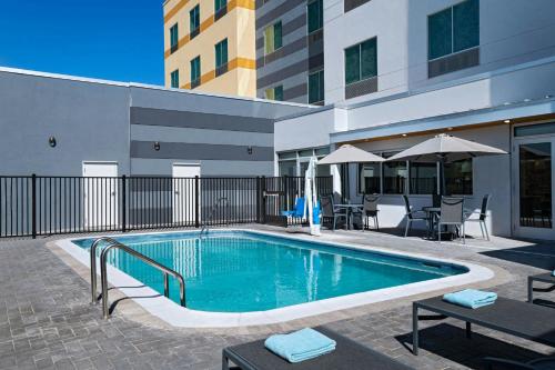 a swimming pool with tables and umbrellas next to a building at Fairfield Inn & Suites by Marriott Harlingen in Harlingen