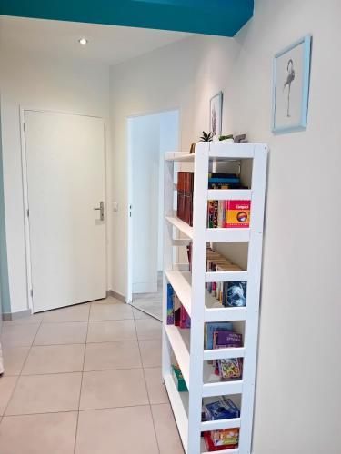 a room with a white book shelf with books at Maison cosy à Pérols - proche plage & Parc Expo Arena - clim, garage in Pérols