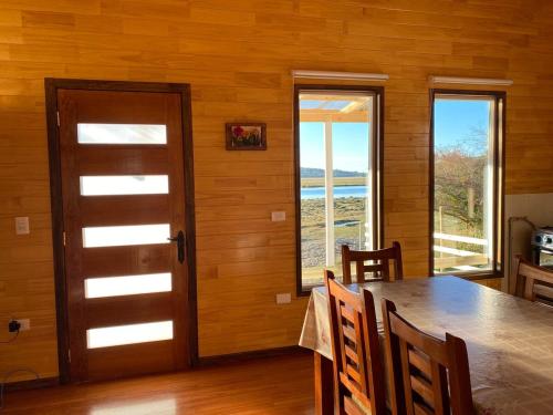 a dining room with a table and some windows at Cabaña Encanto del humedal Aituy in Aytuy