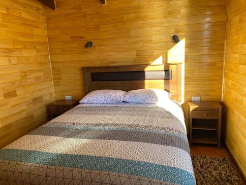 a bedroom with a bed in a wooden room at Cabaña Encanto del humedal Aituy in Aytuy