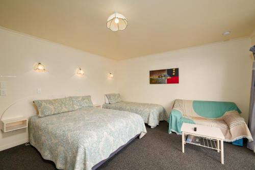 a bedroom with two beds and a chair at Blue Seas Motel in Kaikoura