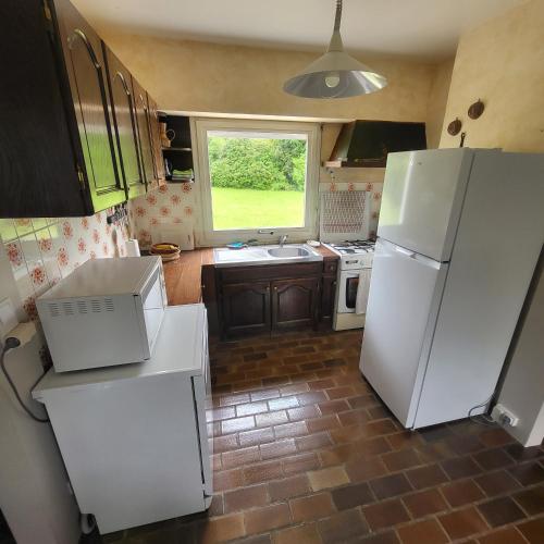 une cuisine avec des appareils blancs et une grande fenêtre dans l'établissement AU GRAND PIN, à Fouesnant