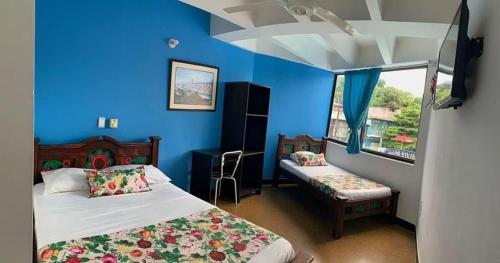 a bedroom with two beds and a blue wall at Hotel la popa in Honda