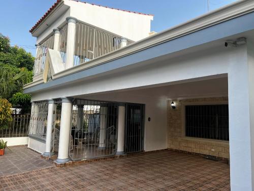 a white house with a gate and a balcony at Residencial los Reyes casa Martinez in Santiago de los Caballeros