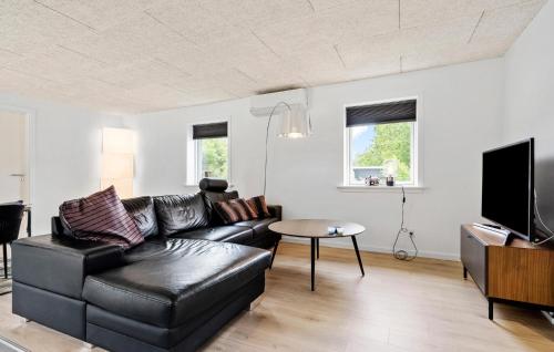 a living room with a black leather couch and a tv at 3 Bedroom Beautiful Home In Tarm in Tarm