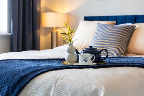 a tray with two cups and a vase on a bed at Oxford Escape - Stylish 3 Bedroom Holiday Home with free parking in Oxford