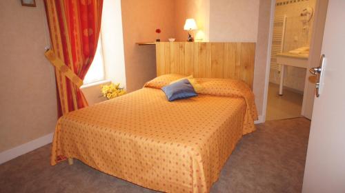 ein Schlafzimmer mit einem Bett mit einem blauen Kissen darauf in der Unterkunft Auberge De Raulhac in Raulhac