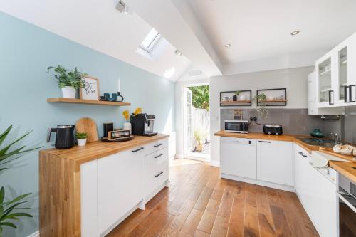a kitchen with white cabinets and a wooden floor at Oxford Escape - Stylish 3 Bedroom Holiday Home with free parking in Oxford