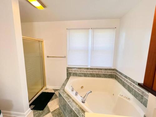 a white bath tub in a bathroom with a window at Cozy 5 bedroom Home mins from RIT in Rochester