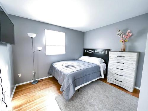 a bedroom with a bed and a dresser and a window at Cozy 5 bedroom Home mins from RIT in Rochester