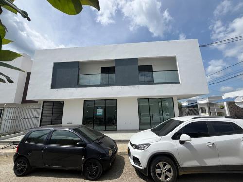 two cars parked in front of a white building at Urvan Studio in Montería