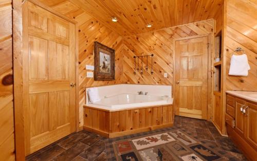 a bathroom with a tub in a wooden wall at Think a Little Less in Gatlinburg